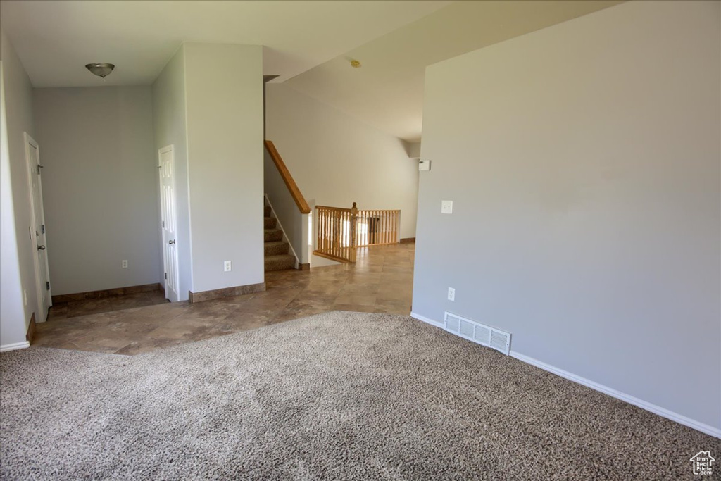 Carpeted spare room with baseboards and stairs