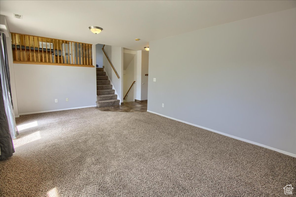 Empty room featuring stairs, carpet flooring, and baseboards