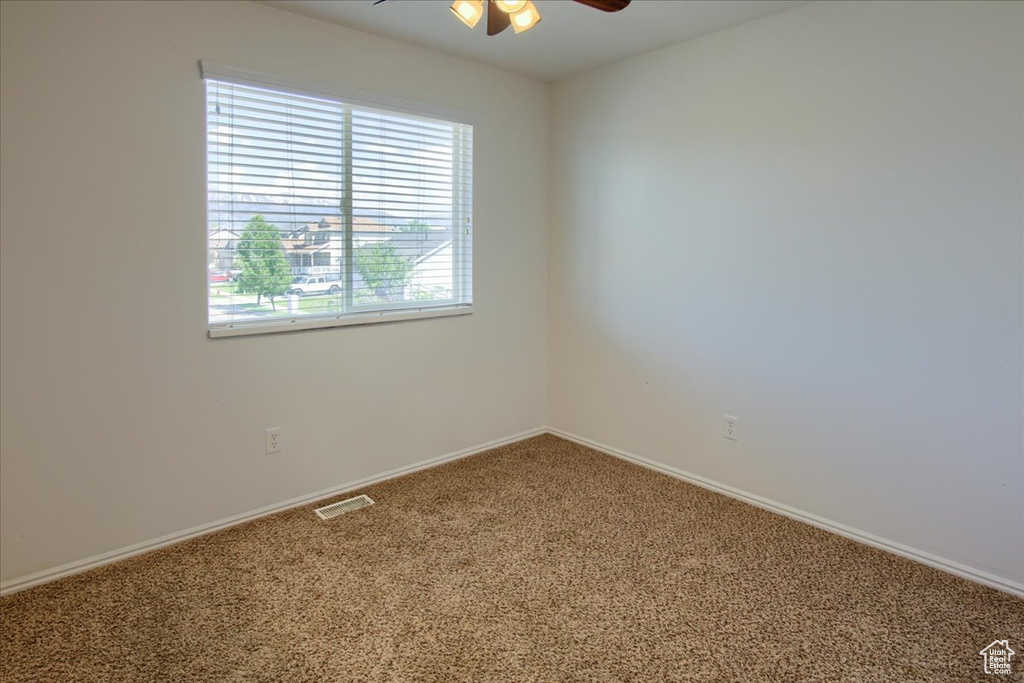Spare room with a ceiling fan, carpet flooring, and baseboards