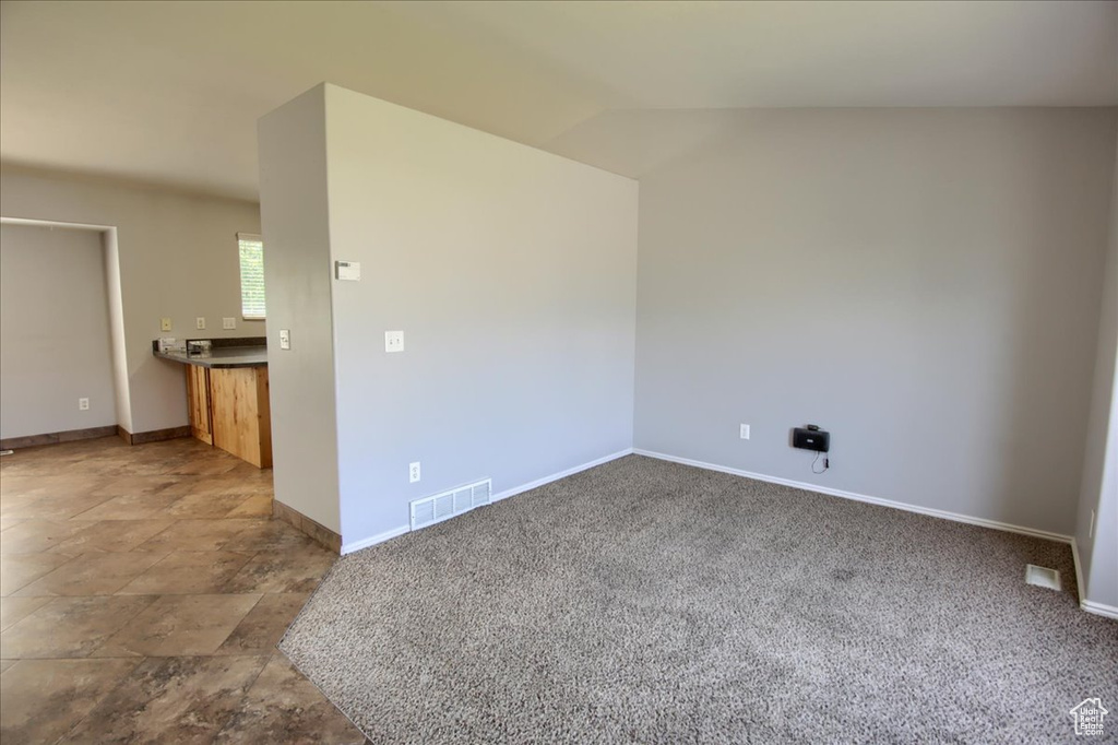 Carpeted empty room with baseboards and lofted ceiling