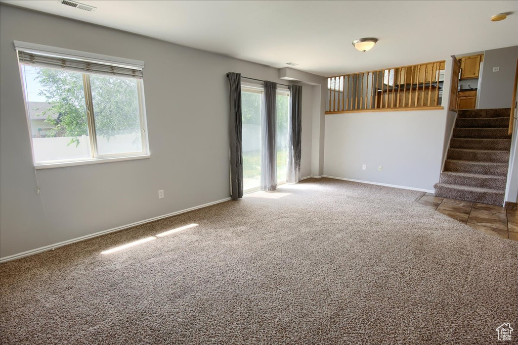 Unfurnished living room with carpet flooring, stairs, and baseboards