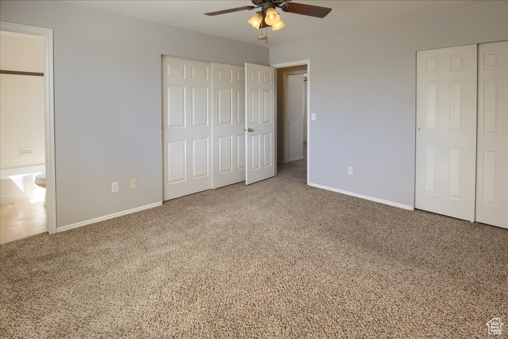 Unfurnished bedroom with baseboards, two closets, carpet floors, and ceiling fan