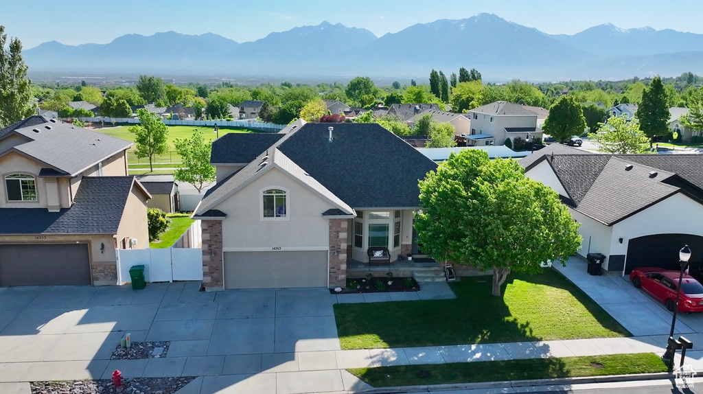 View of front of house featuring a garage, driveway, stucco siding, a mountain view, and a residential view