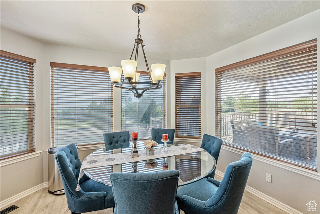 Dining area featuring a chandelier, baseboards, light wood-style floors, and healthy amount of natural light