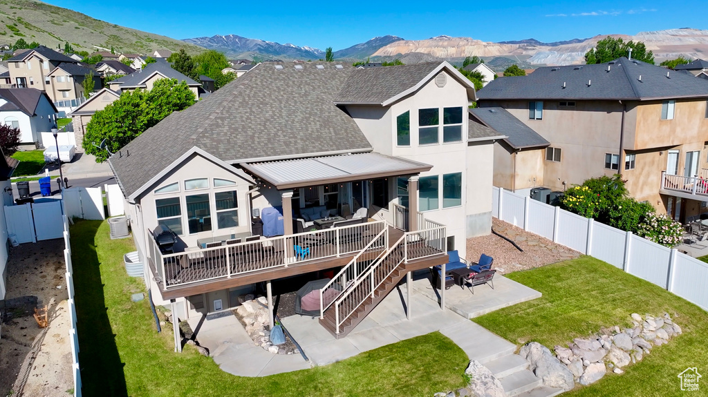 Rear view of house featuring a patio, a shingled roof, stucco siding, and a deck with mountain view