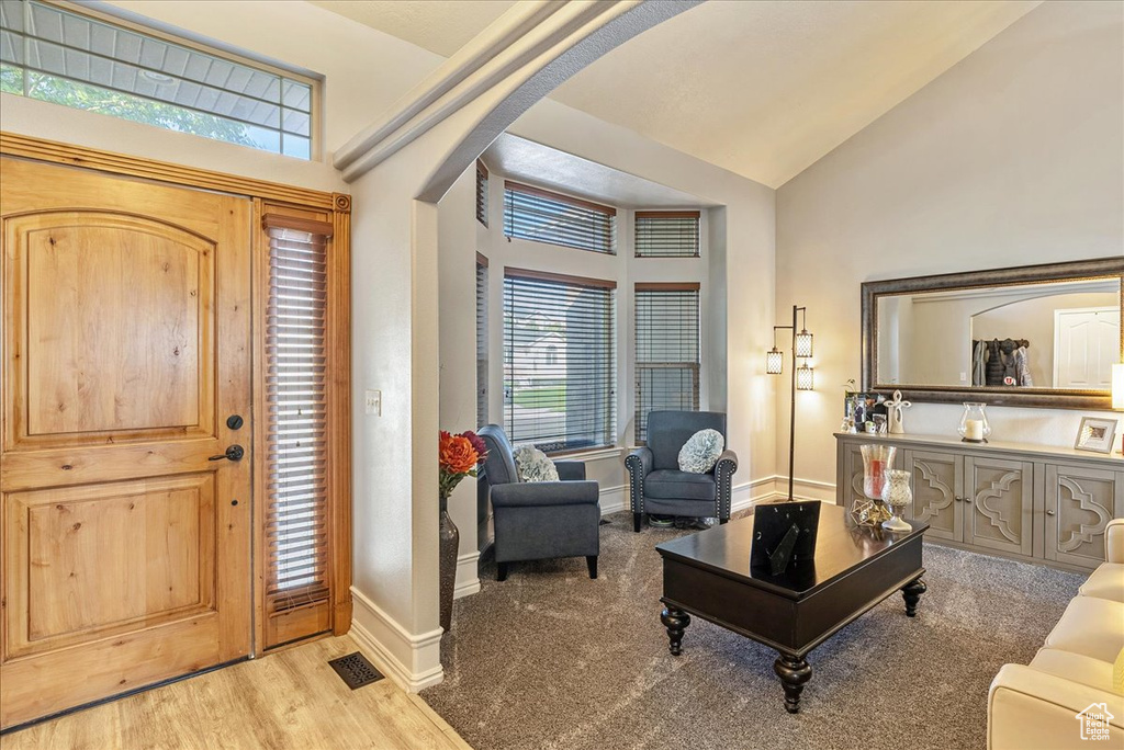 Foyer entrance with arched walkways, vaulted ceiling, wood finished floors, and baseboards