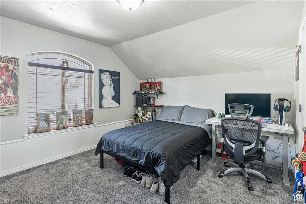 Bedroom with carpet floors, vaulted ceiling, a desk, and baseboards