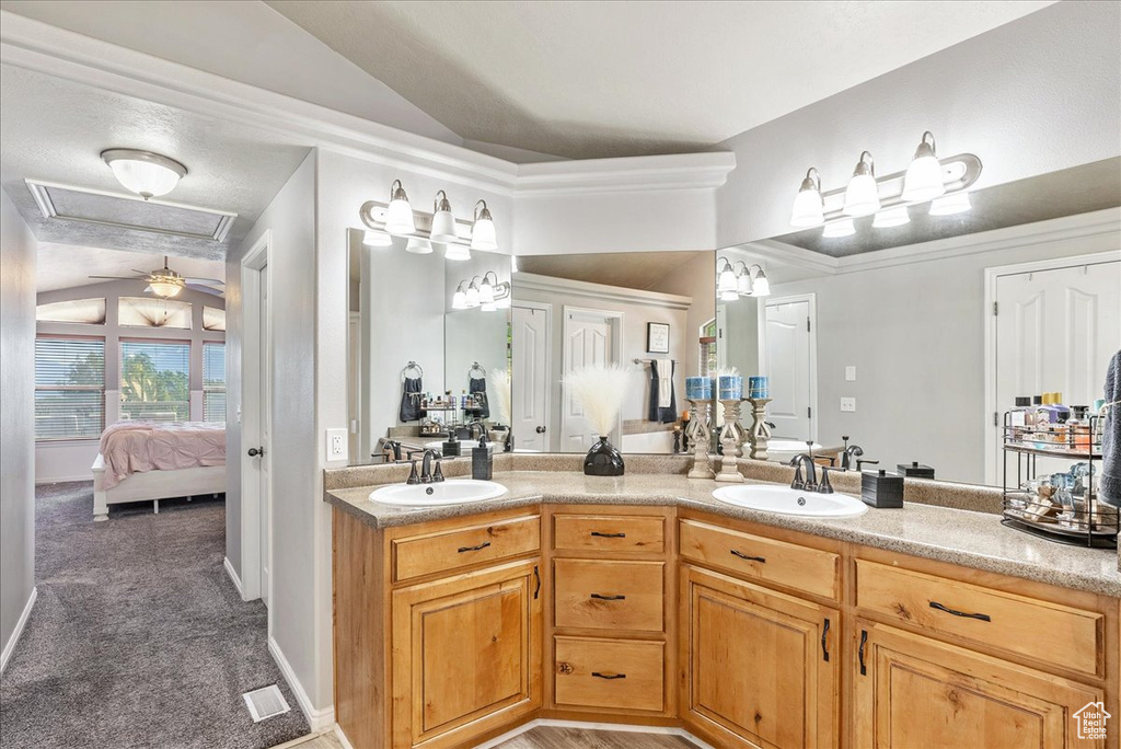 Ensuite bathroom featuring double vanity and lofted ceiling