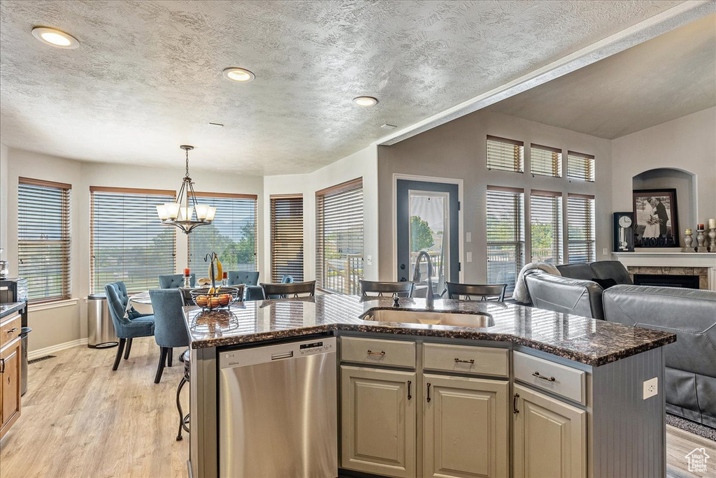 Kitchen with dishwasher, a sink, open floor plan, an island with sink, and a chandelier