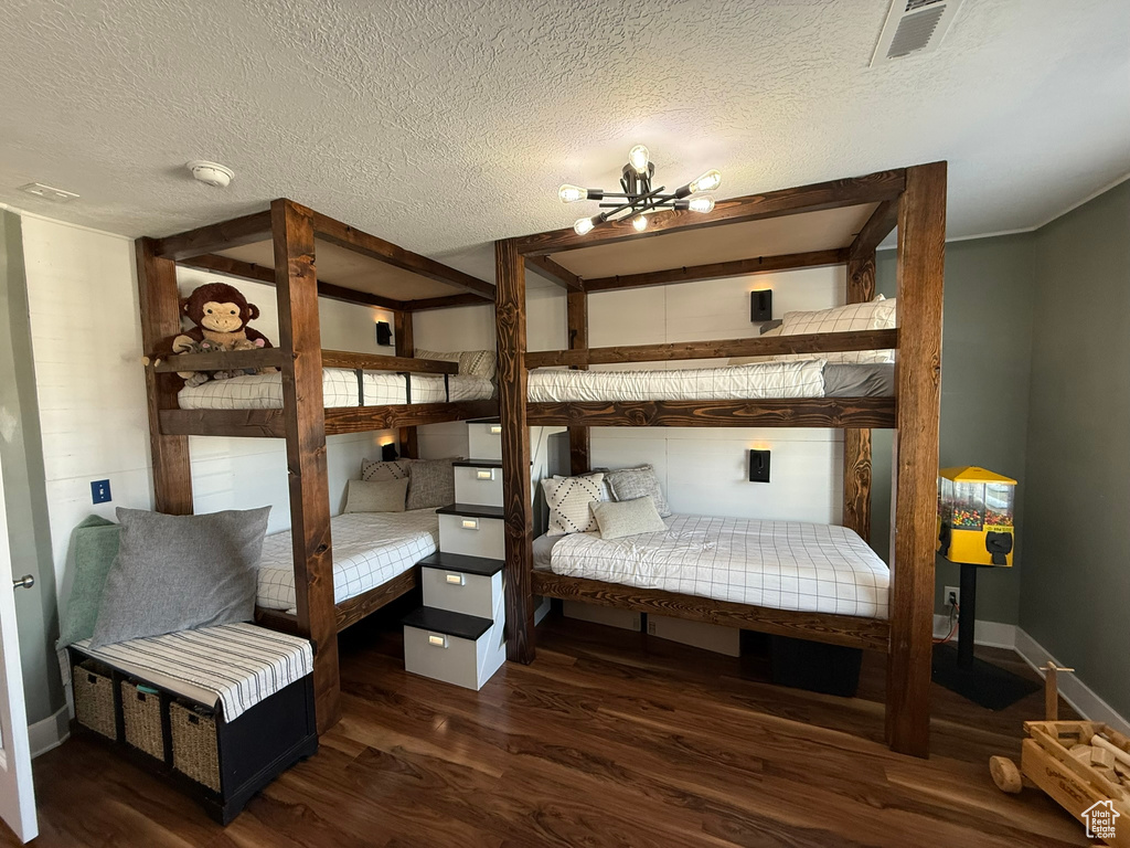 Bedroom with wood finished floors, a chandelier, a textured ceiling, and baseboards