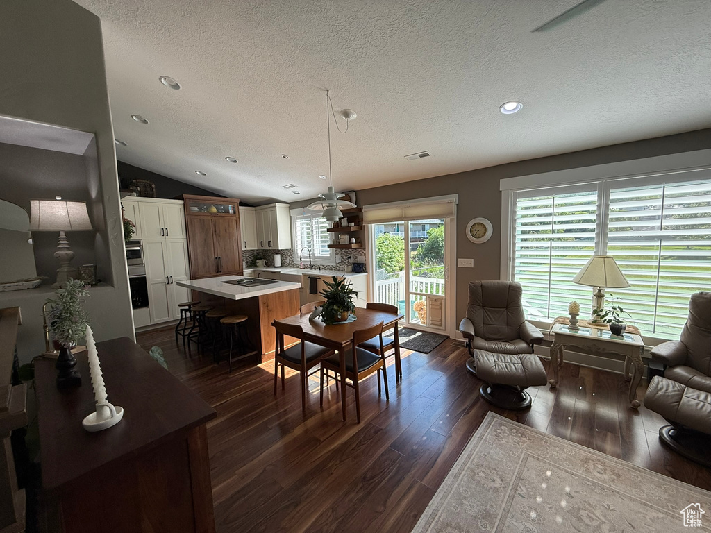 Living room featuring dark wood-style flooring, a textured ceiling, recessed lighting, and lofted ceiling