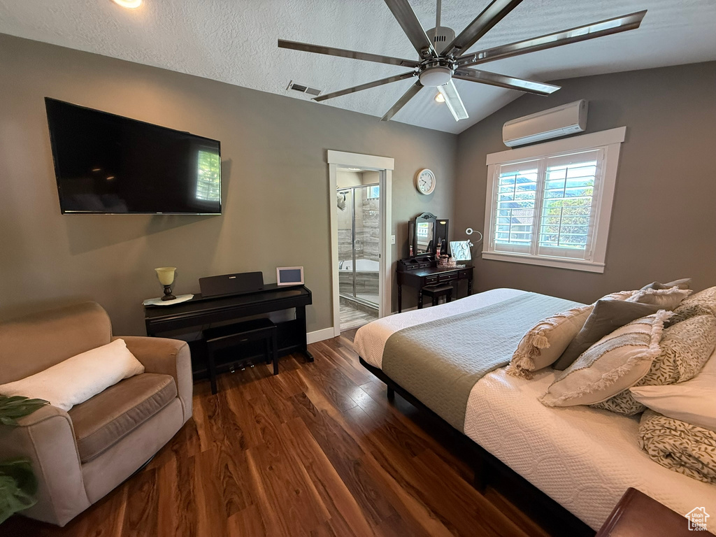 Bedroom featuring a wall mounted AC, wood finished floors, vaulted ceiling, baseboards, and ensuite bathroom