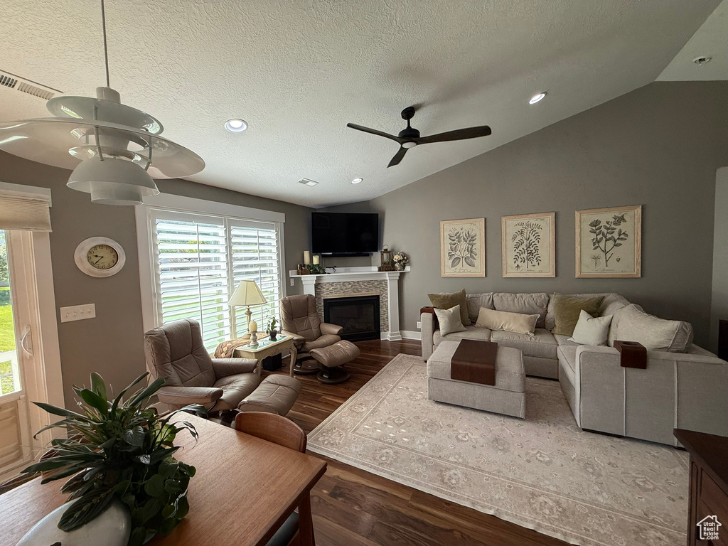 Living room featuring ceiling fan, lofted ceiling, healthy amount of natural light, wood finished floors, and a tile fireplace