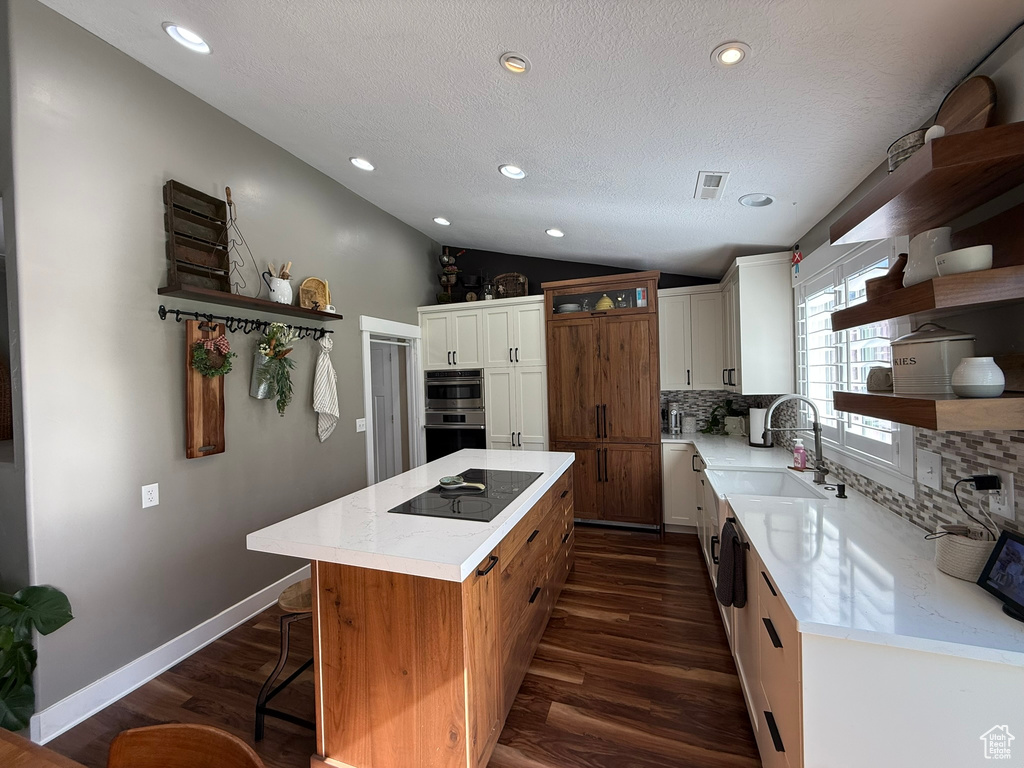 Kitchen featuring open shelves, black electric stovetop, a sink, dark wood-style floors, and vaulted ceiling