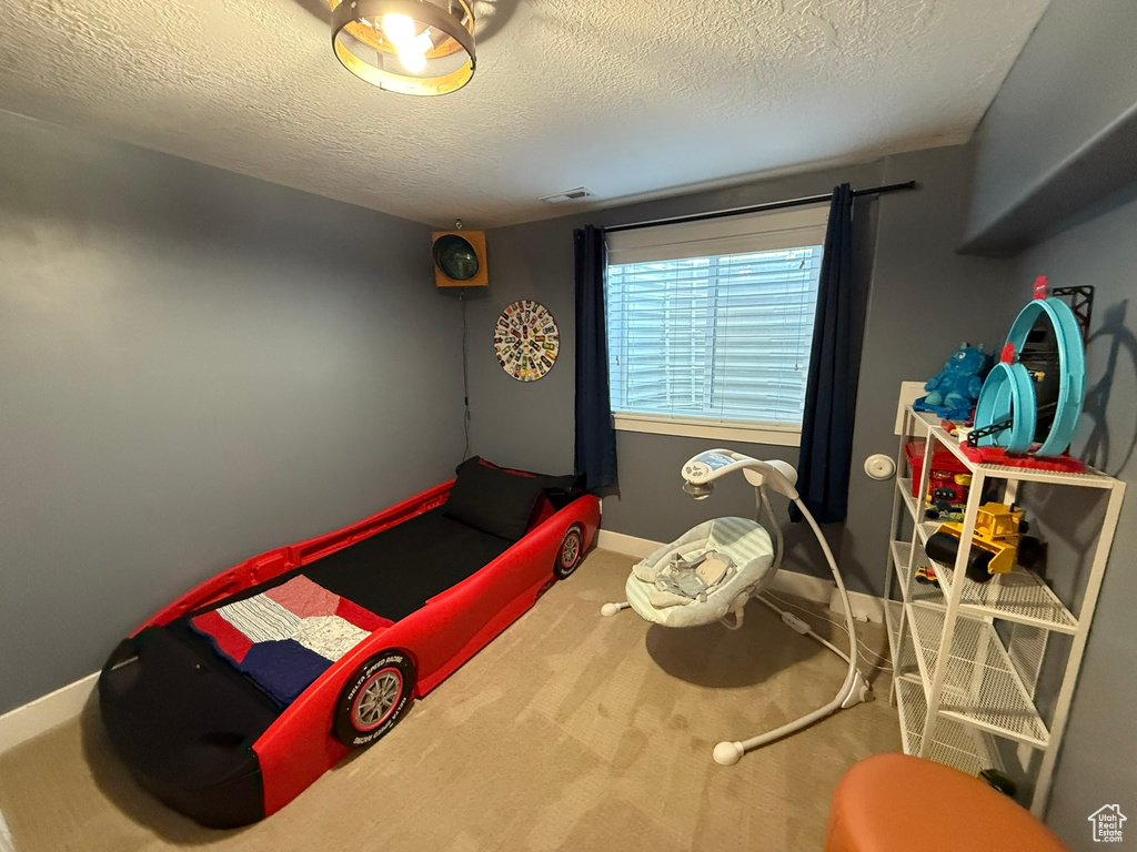 Carpeted bedroom with a textured ceiling and baseboards