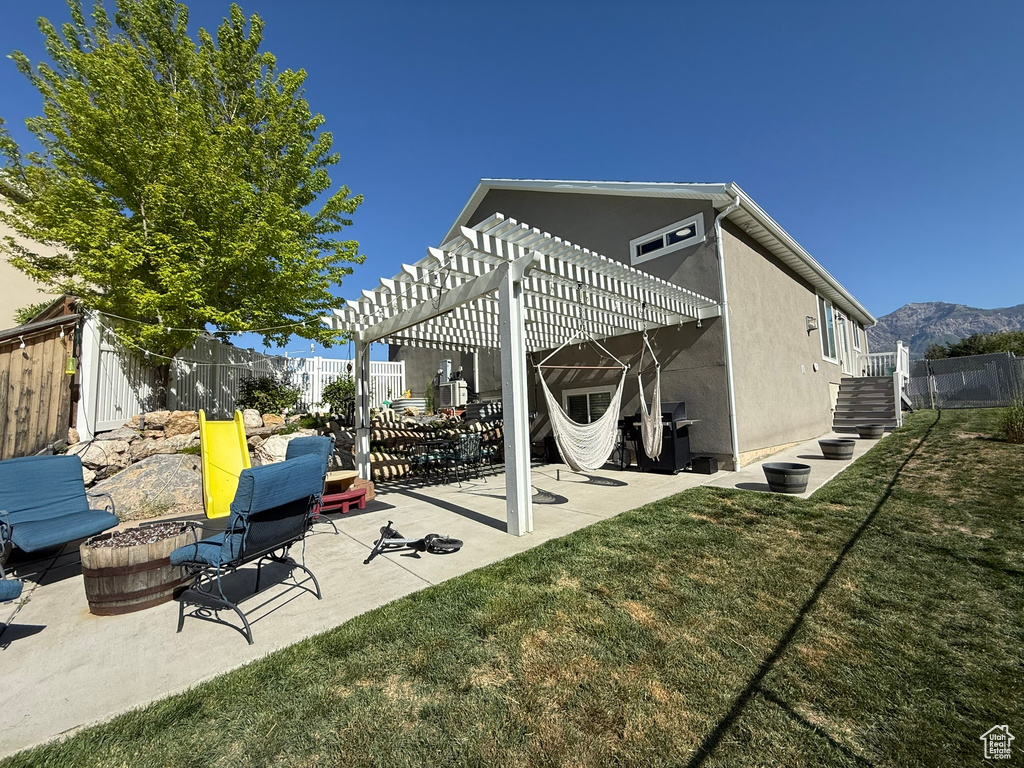 Back of property with stucco siding, a pergola, a patio, and a mountain view