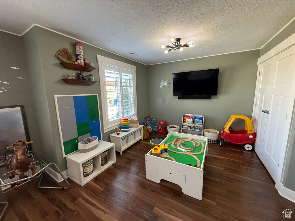 Recreation room featuring wood finished floors, a textured ceiling, crown molding, and baseboards