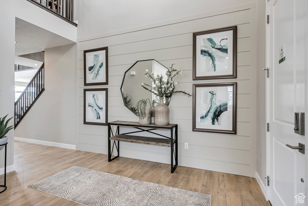 Entrance foyer with light wood-style flooring, stairway, wooden walls, and baseboards