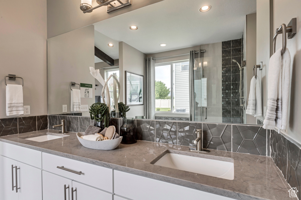 Full bath with tasteful backsplash, double vanity, recessed lighting, and a tile shower