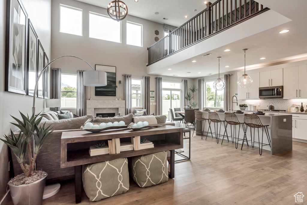 Living area with light wood-type flooring, a fireplace, a towering ceiling, recessed lighting, and a chandelier