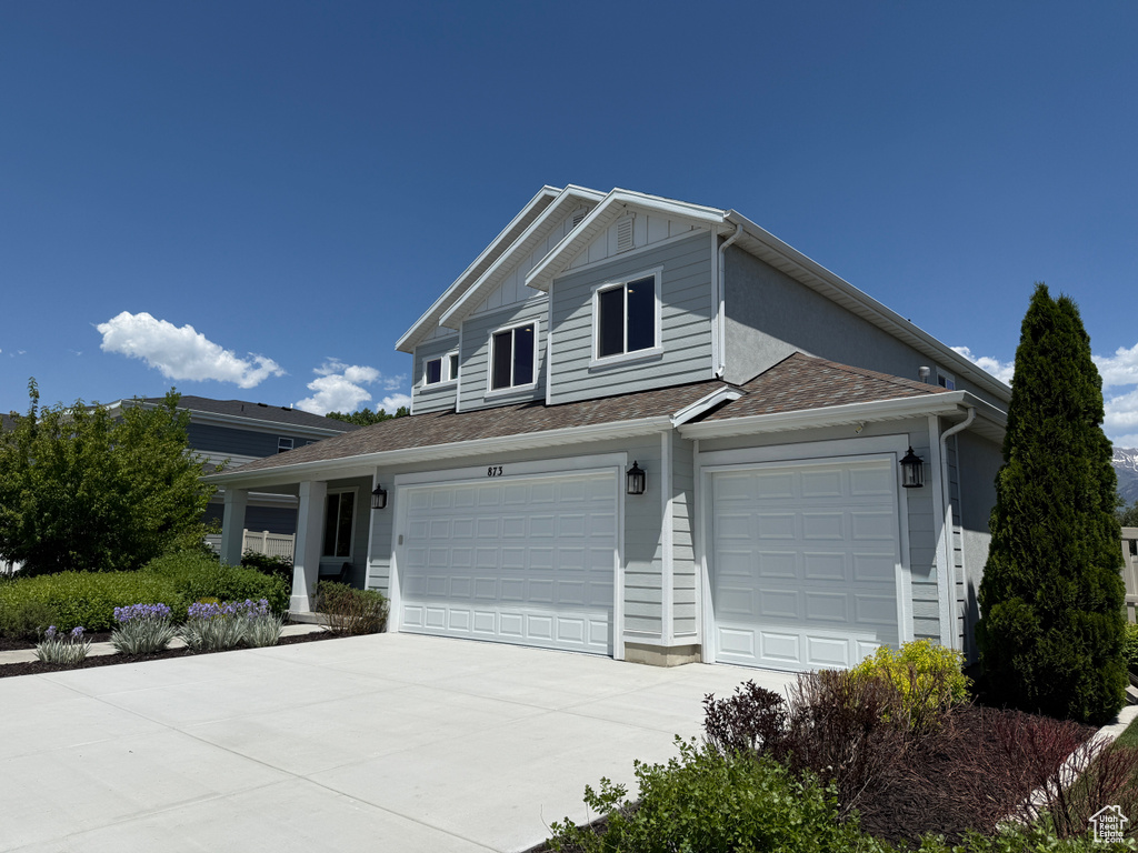 View of front of property with driveway, board and batten siding, and an attached garage