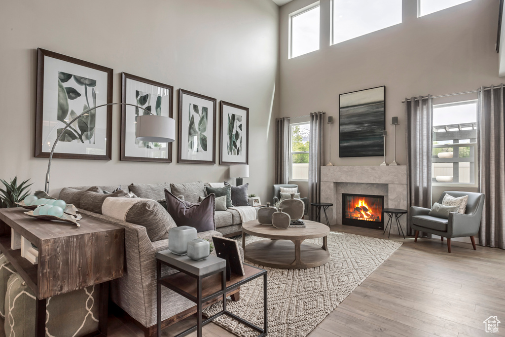 Living area featuring healthy amount of natural light, a tile fireplace, a towering ceiling, and wood finished floors