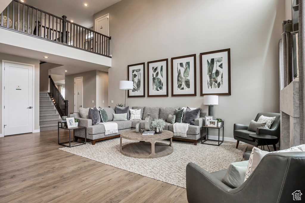Living area with a towering ceiling, stairway, wood finished floors, baseboards, and recessed lighting