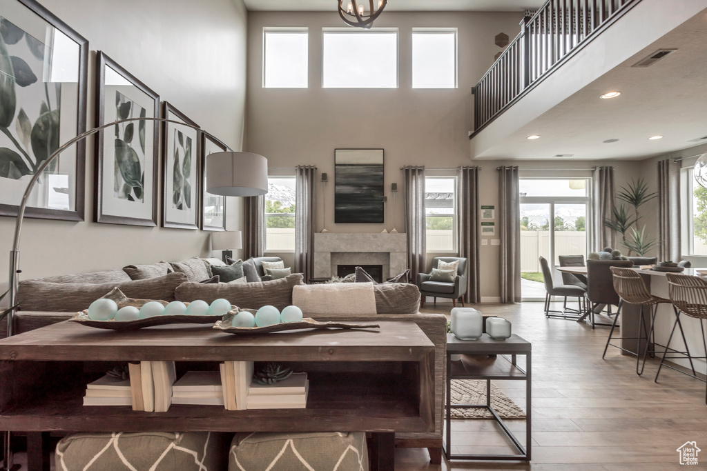 Living area featuring wood finished floors, a towering ceiling, a fireplace, and recessed lighting