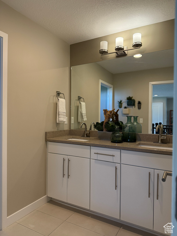 Bathroom with double vanity, tile patterned floors, and baseboards