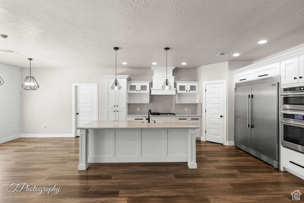 Kitchen with built in refrigerator, a textured ceiling, baseboards, recessed lighting, and tasteful backsplash