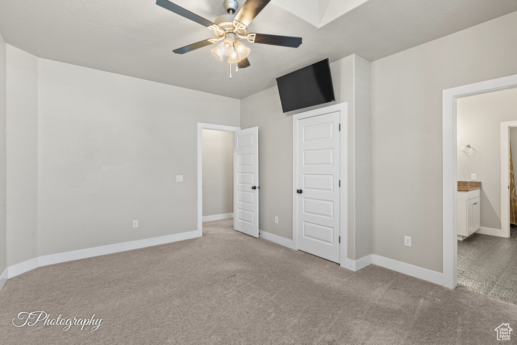 Unfurnished bedroom with carpet floors, baseboards, ensuite bath, and a ceiling fan