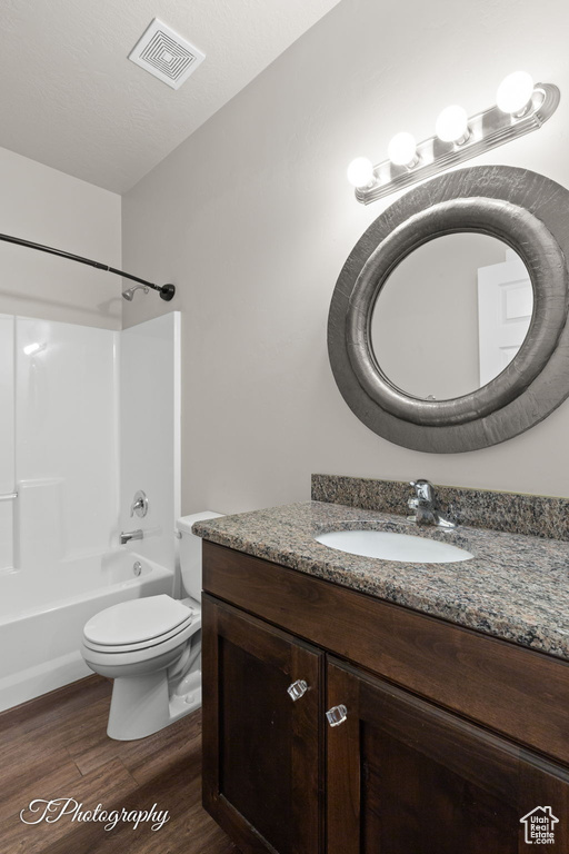 Bathroom with vanity, wood finished floors, tub / shower combination, and toilet