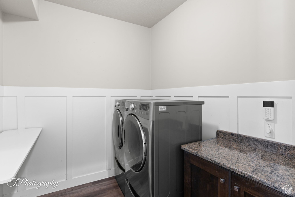 Laundry room with independent washer and dryer, dark wood finished floors, wainscoting, and a decorative wall
