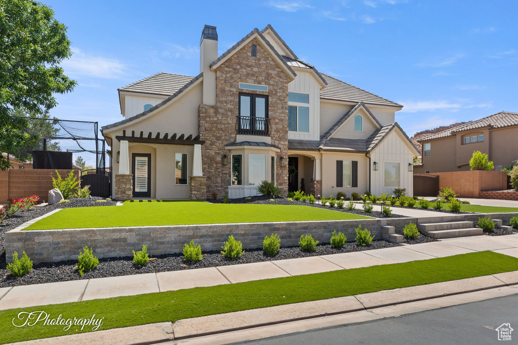 View of front of home featuring stone siding, stucco siding, and a chimney