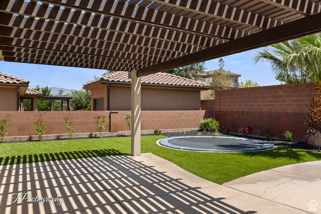 View of patio with a trampoline, a pergola, and a mountain view
