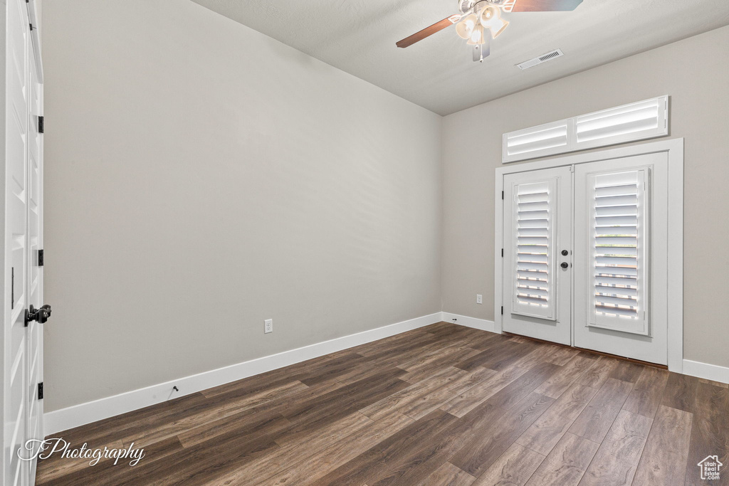 Empty room featuring a ceiling fan, dark wood-style floors, and baseboards