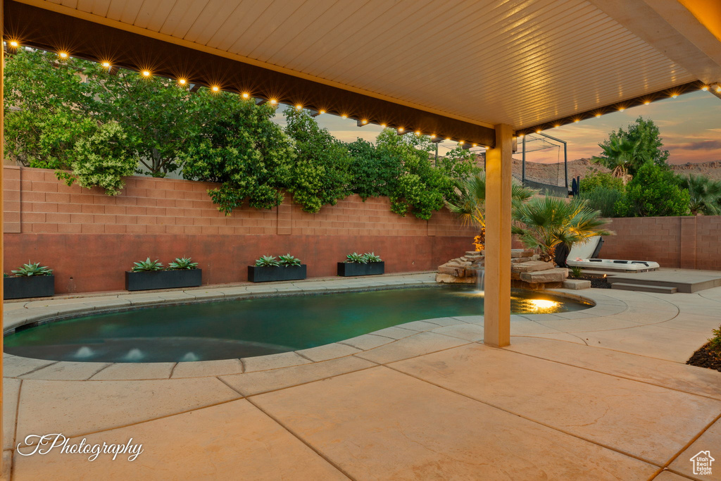 Pool at dusk featuring a patio area and a fenced backyard