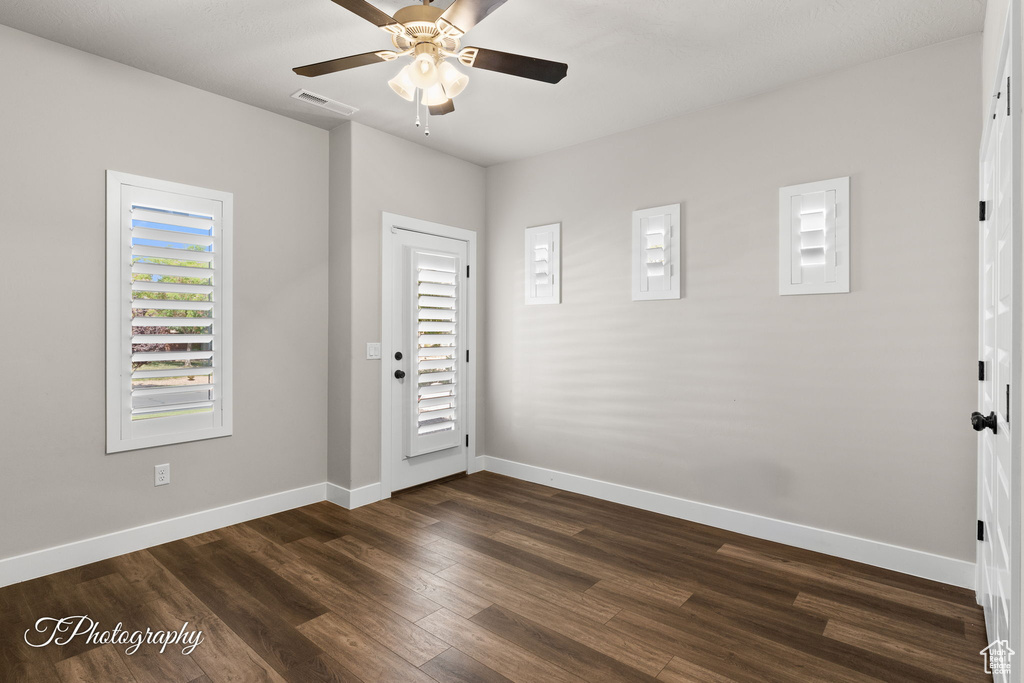 Unfurnished room featuring ceiling fan, baseboards, and dark wood-type flooring