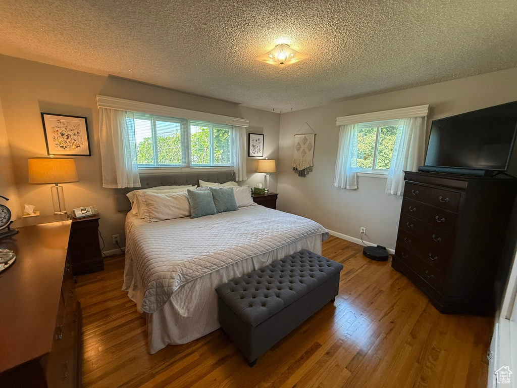 Bedroom featuring wood finished floors, a textured ceiling, and baseboards