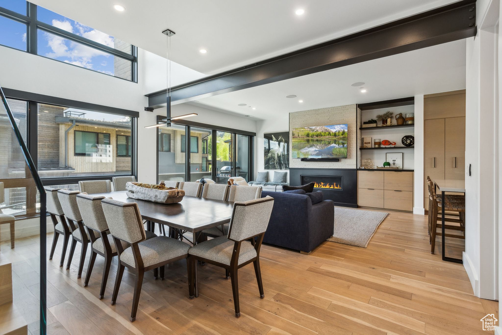 Dining room featuring light wood-style flooring, a large fireplace, and recessed lighting