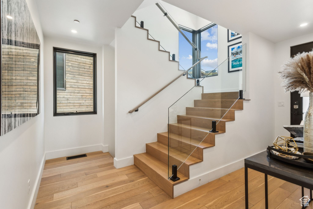 Staircase featuring wood finished floors, baseboards, and recessed lighting