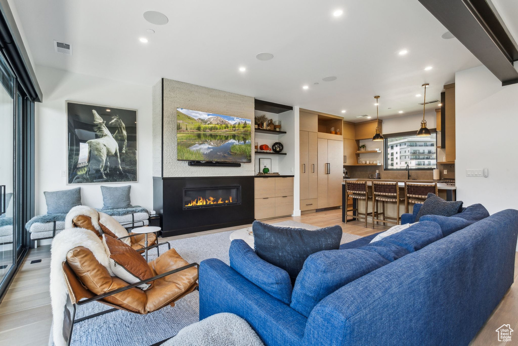 Living area with light wood-style floors, recessed lighting, and a fireplace