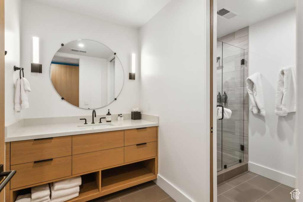 Bathroom featuring vanity, a shower stall, tile patterned floors, and baseboards