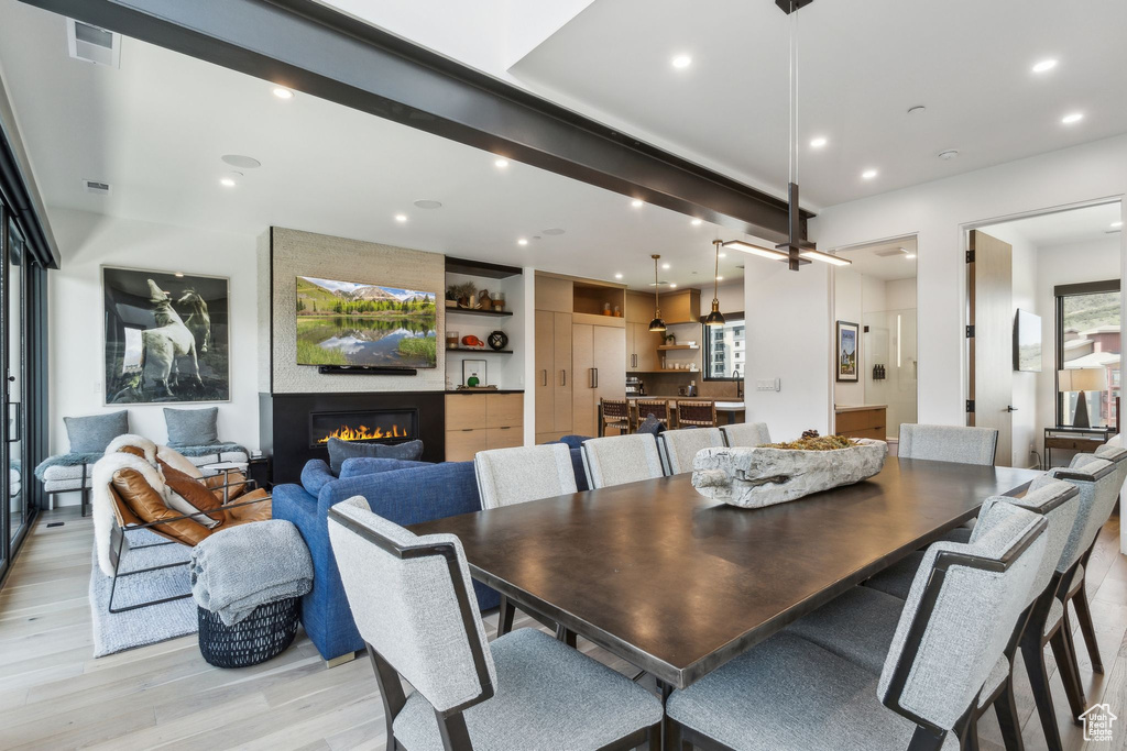 Dining area with light wood-style floors, a fireplace, and recessed lighting