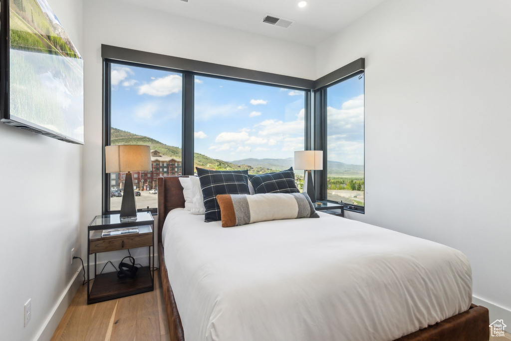 Bedroom with wood finished floors, multiple windows, baseboards, recessed lighting, and a mountain view