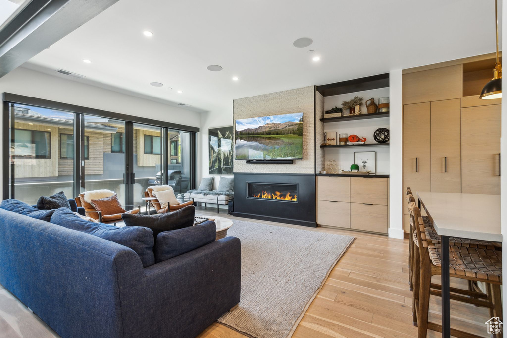 Living area featuring light wood-style floors, a large fireplace, and recessed lighting