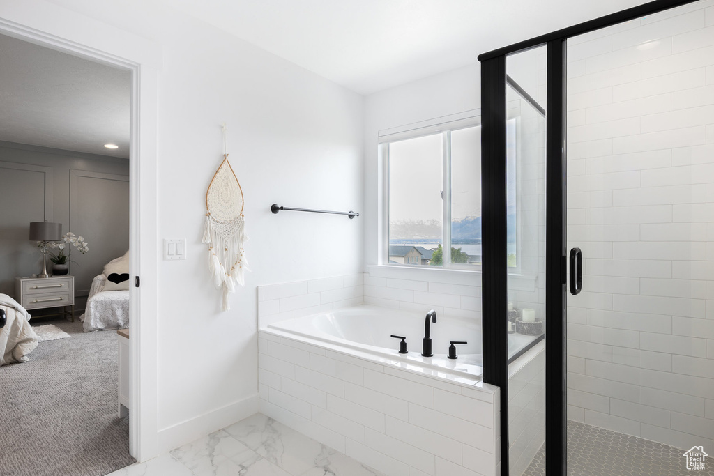 Full bath featuring connected bathroom, a garden tub, a stall shower, and baseboards