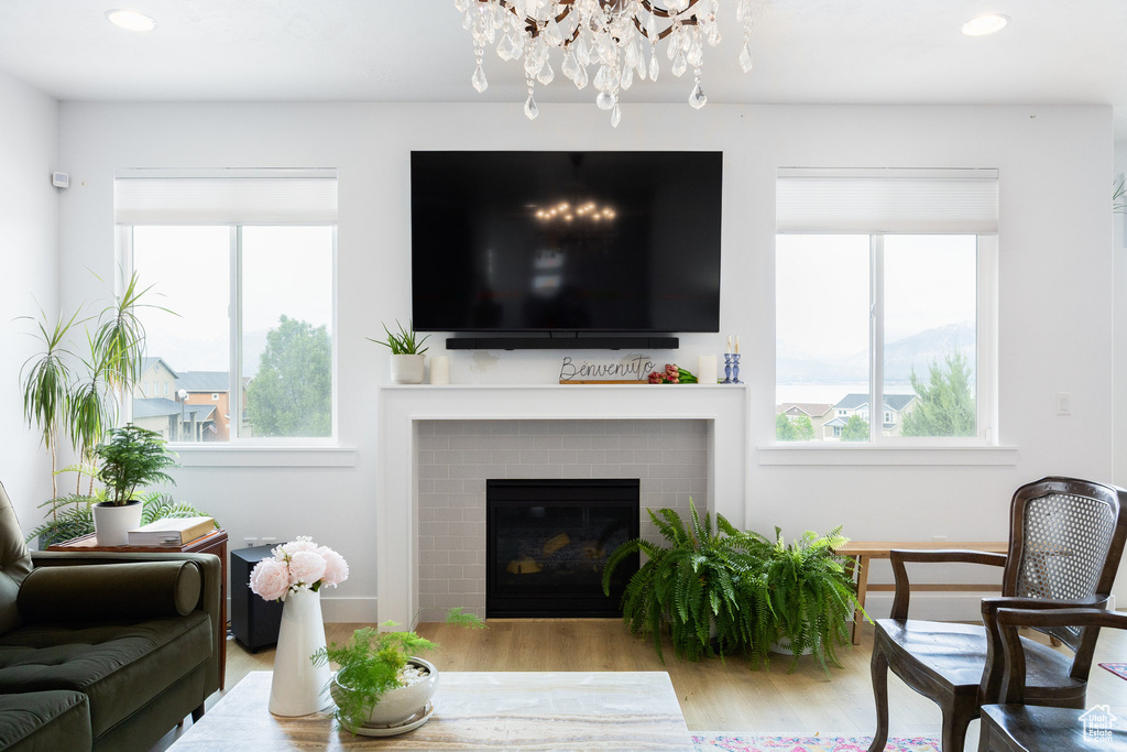 Living room with a chandelier, wood finished floors, a brick fireplace, recessed lighting, and baseboards