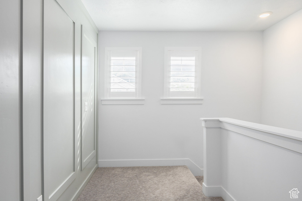 Corridor with carpet floors, baseboards, and an upstairs landing