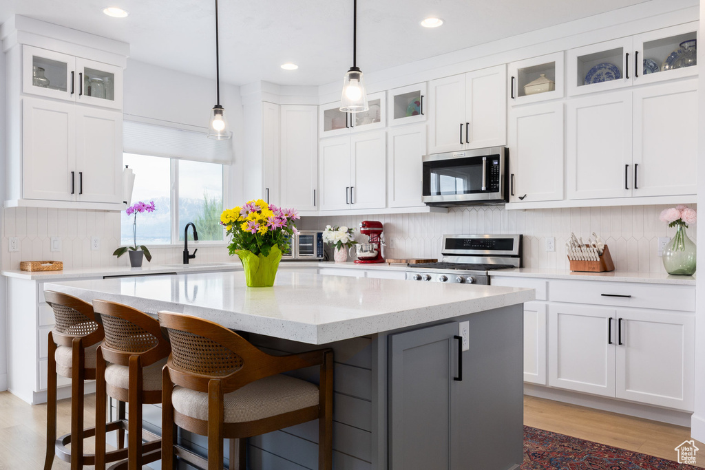 Kitchen featuring stainless steel appliances, a center island, white cabinets, tasteful backsplash, and a breakfast bar
